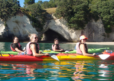 happy sea kayakers on calm water with cliffs in background