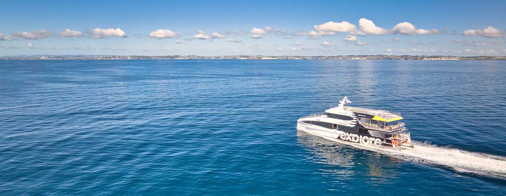 white catamaran ferry zooming along on blue ocean